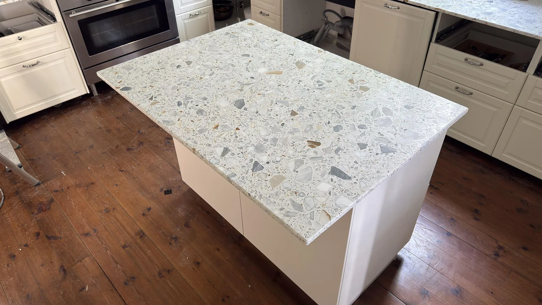 Köksö i Terrazzo Calacatta i ett kök i Stockholm, där den spräckliga ytan med marmorflis i grått och brunt syns ovanifrån.