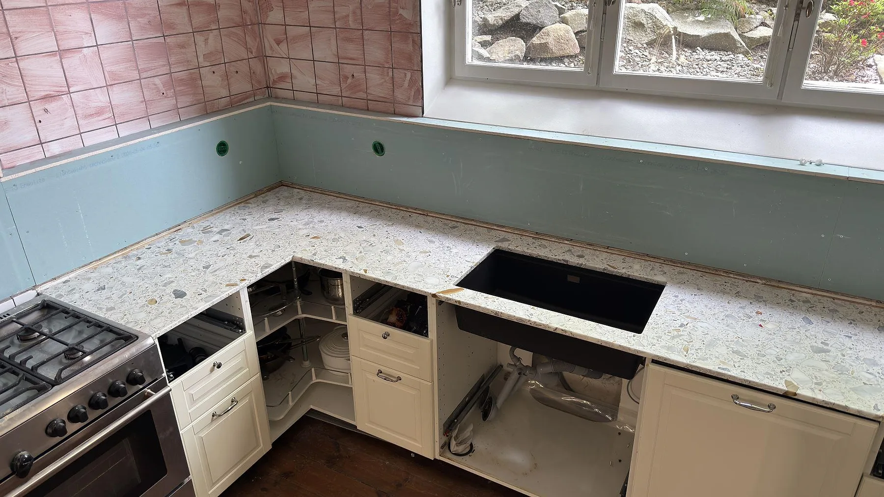 Nedsänkt diskho i en köksbänkskiva av Terrazzo Calacatta under fönstret i ett kök i Stockholm.