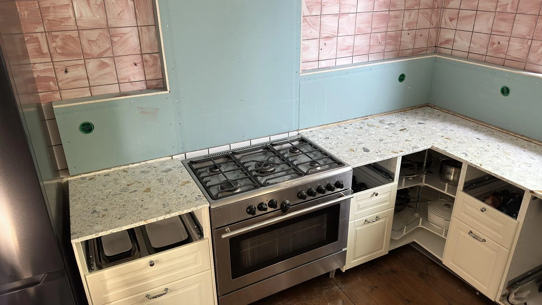 Fristående spis i rostfritt intill en köksbänkskiva i Terrazzo Calacatta i ett kök i Stockholm.