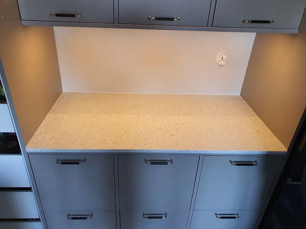Köksbänkskiva i Terrazzo Carrara, matt finish med spräcklig stenstruktur och uppvikt stänkkant mot väggen, i ett kök i Hägersten.