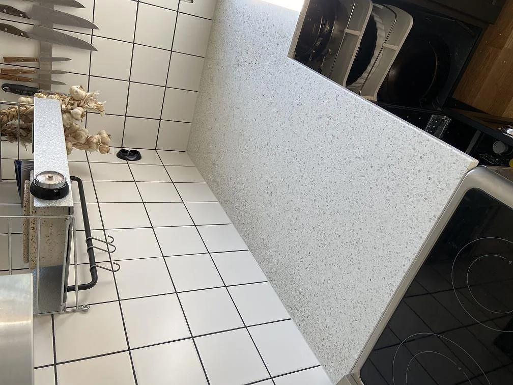 Polerad köksbänkskiva i Terrazzo Carrara med fristående induktionsspis i ett kök under montering i Lund.