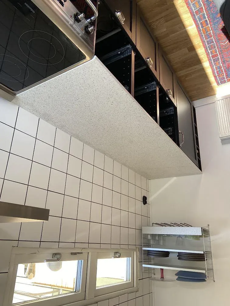 Lång bänkskiva i Terrazzo Carrara med synliga marmorflisor och underliggande köksstommar i ett kök i Lund.