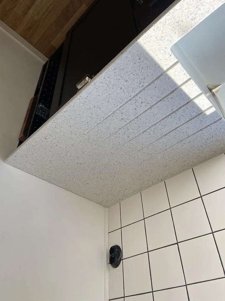 Närbild på ytan av en köksbänkskiva i Terrazzo Carrara med marmorflisor och underlimmad diskho i Lund.