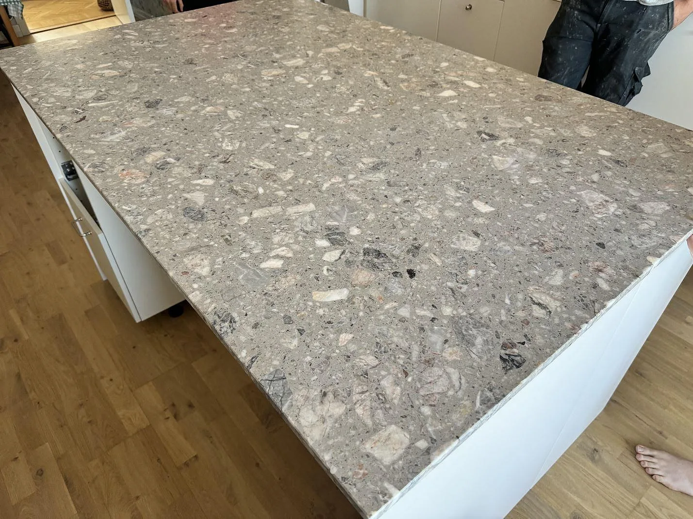 Detaljbild av 20 mm matt Terrazzo Fior Di Pesco på köksö, med tydliga stenfragment och vit stomme i Malmö.