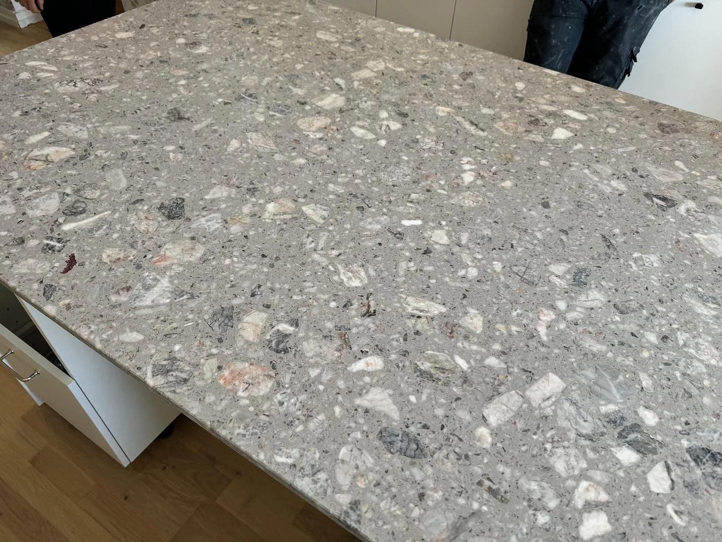 Tät bild av den matta Terrazzo Fior Di Pesco-bänkskivan på köksö i Malmö, med grå bas och ljusa stenfragment.