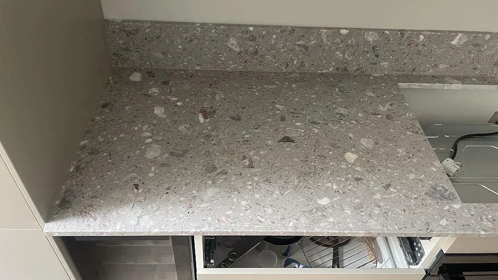 Närbild på matt köksbänkskiva i Terrazzo Fior Di Pesco med uppvikt stänkkant och synliga stenfragment i Malmö.
