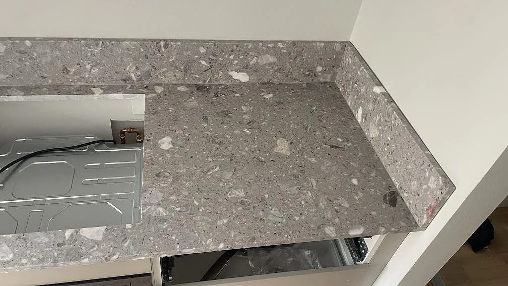 Hörnparti i matt Terrazzo Fior Di Pesco med uppvikt stänkkant och grå terrazzoyta i ett kök i Malmö.