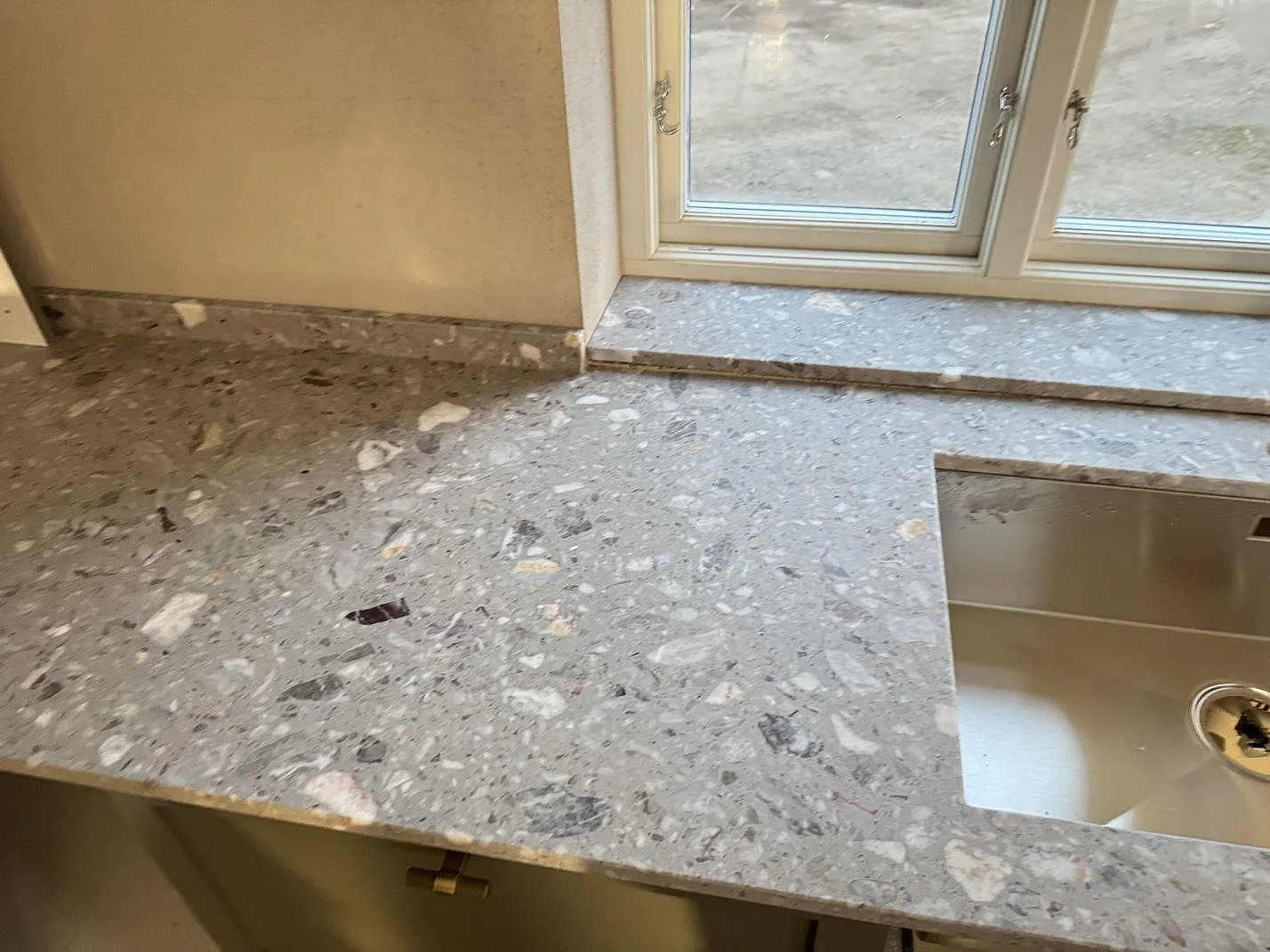 Matt köksbänkskiva i Terrazzo Fior Di Pesco vid fönster och rostfri diskho i Sankt olof.