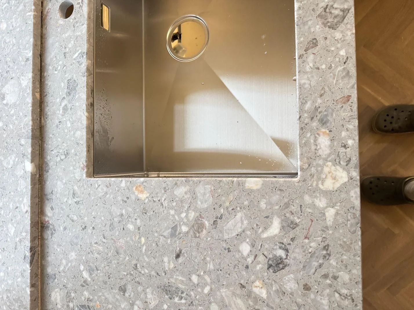 Detaljbild av matt Terrazzo Fior Di Pesco runt rostfri diskho i ett kök i Sankt olof.
