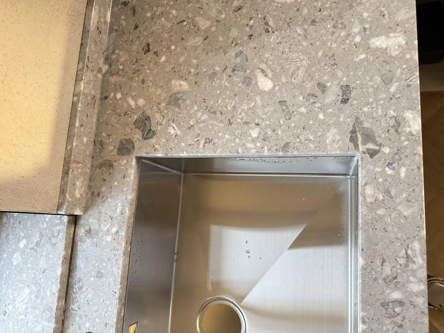 Nära yta i matt Terrazzo Fior Di Pesco med stenens ljusa och grå ballast synlig vid diskhon i Sankt olof.