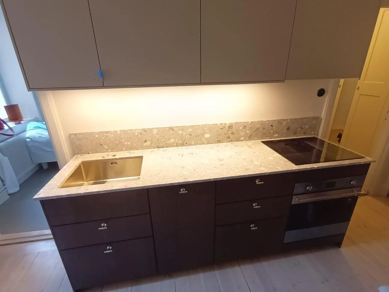 Köksbänkskiva i matt Terrazzo Fior Di Pesco med låg stänkkant, diskho och häll i ett kök i Stockholm.