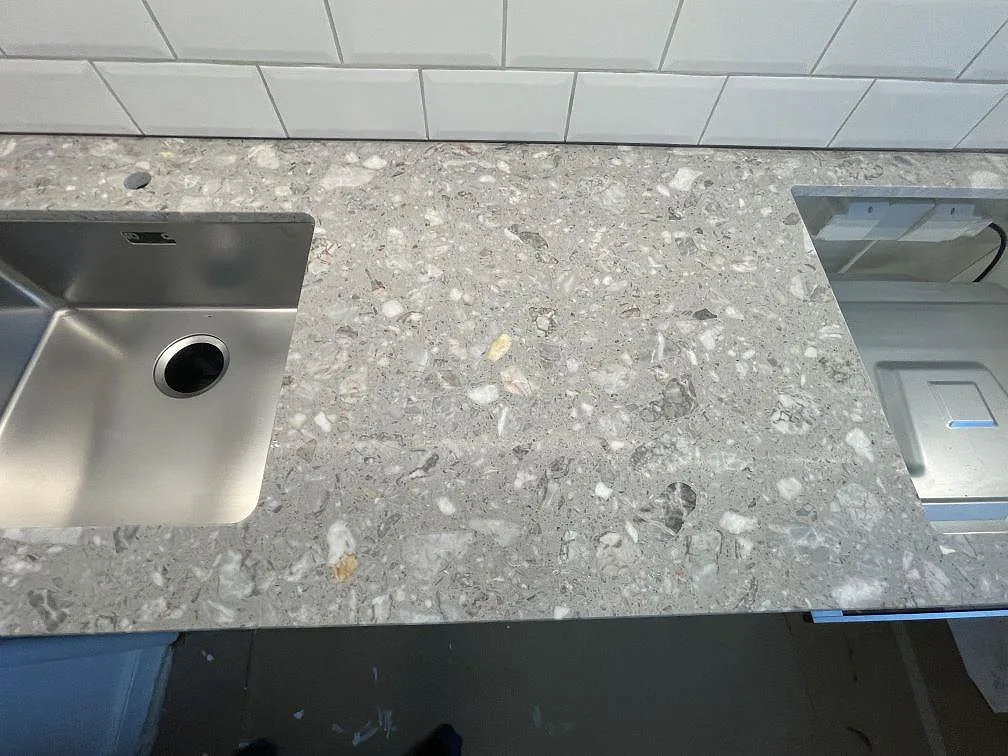 Närbild av matt Terrazzo Fior Di Pesco som köksbänkskiva med rostfri diskho och hällöppning i Stockholm.