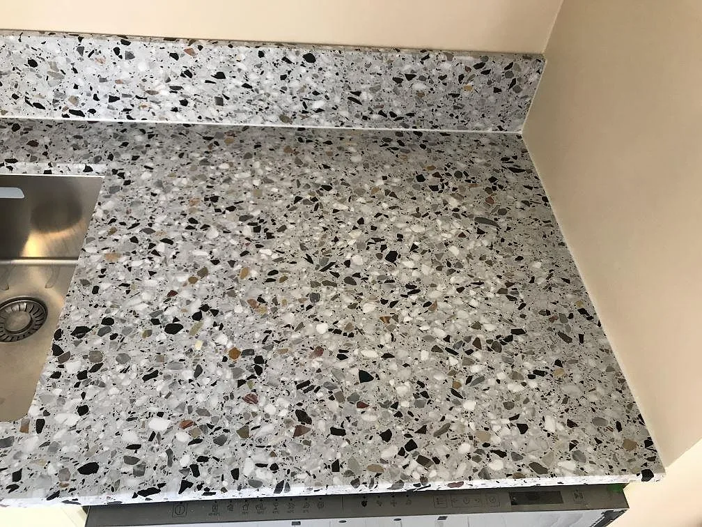 Matt terrazzobänkskiva i Terrazzo GV med underlimmad rostfri diskho och uppvikt stänkkant i ett kök i Göteborg.
