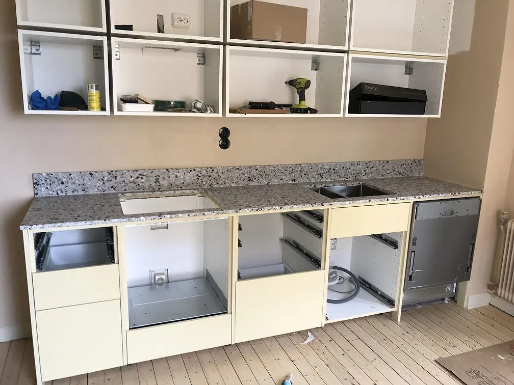 Köksbänkskiva i ljus terrazzo, Terrazzo GV, matt yta, monterad längs en köksrad med urtagning för diskho och häll i ett kök i Göteborg under montering.