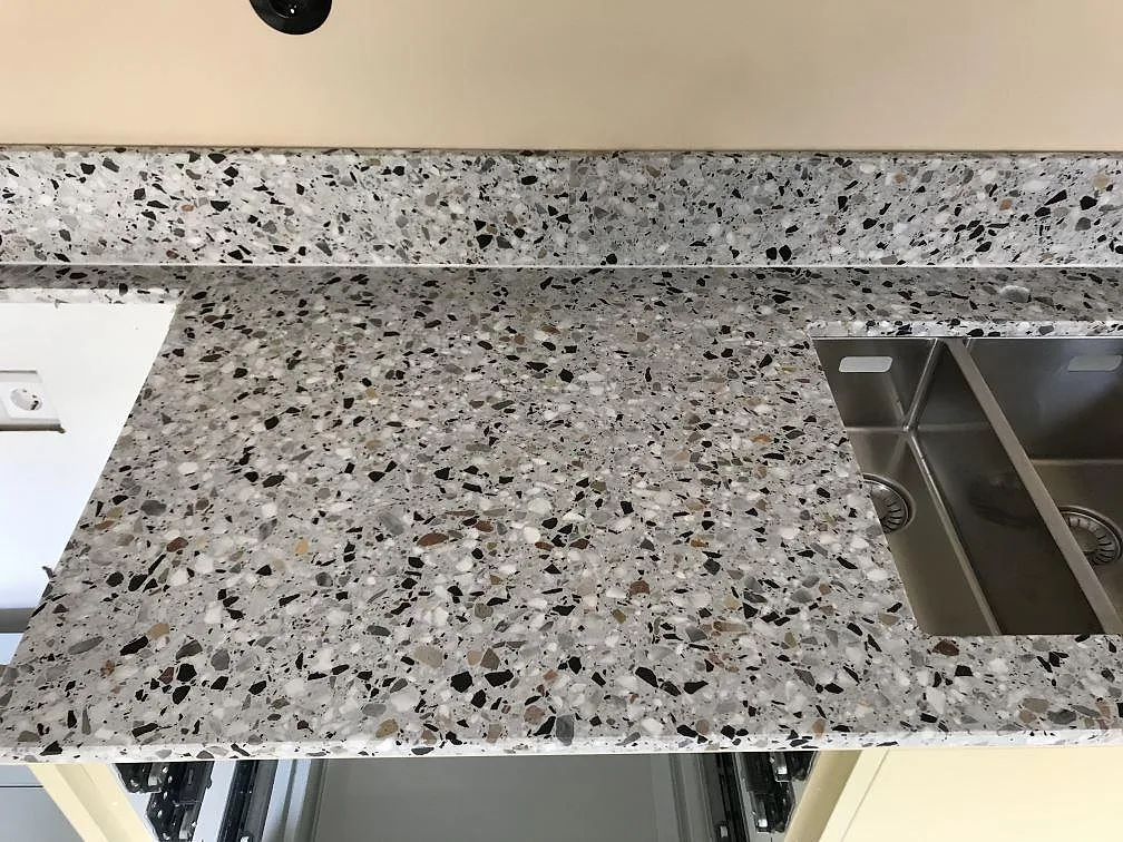 Närbild på den matta terrazzoytan i Terrazzo GV med marmor- och granitflisor vid en urtagning i ett kök i Göteborg.