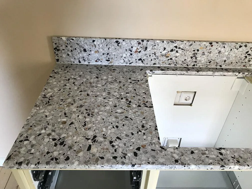 Hörnparti av terrazzobänkskiva i Terrazzo GV med uppvikt stänkkant mot väggen i ett kök i Göteborg.