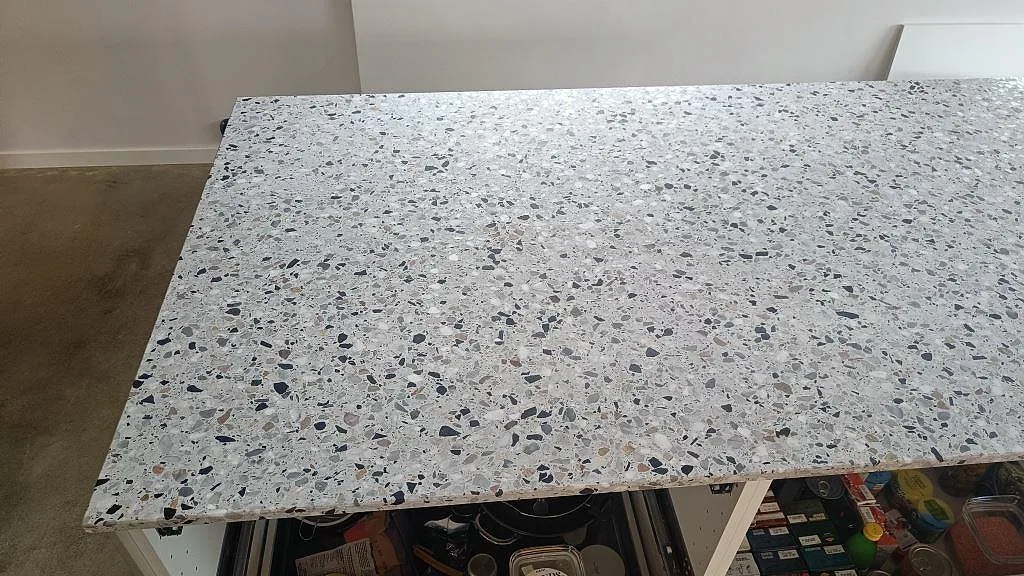 Detalj av bred köksö i Terrazzo GV, Matt, med synlig svart och grå ballast i kök i Malmö.