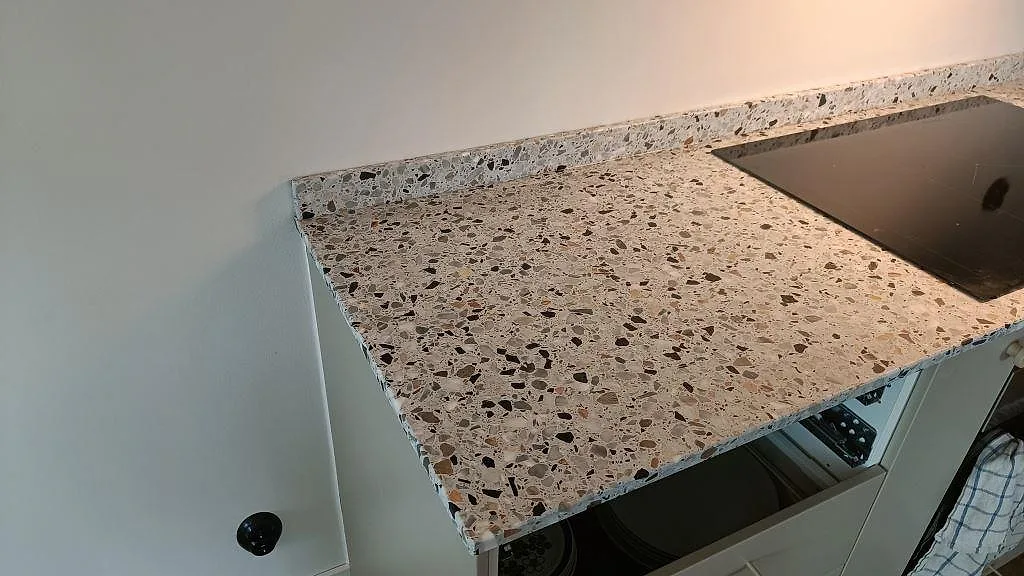 Bänkskiva i Terrazzo GV, Matt, med uppvikt stänkkant och svart häll i kök i Malmö.