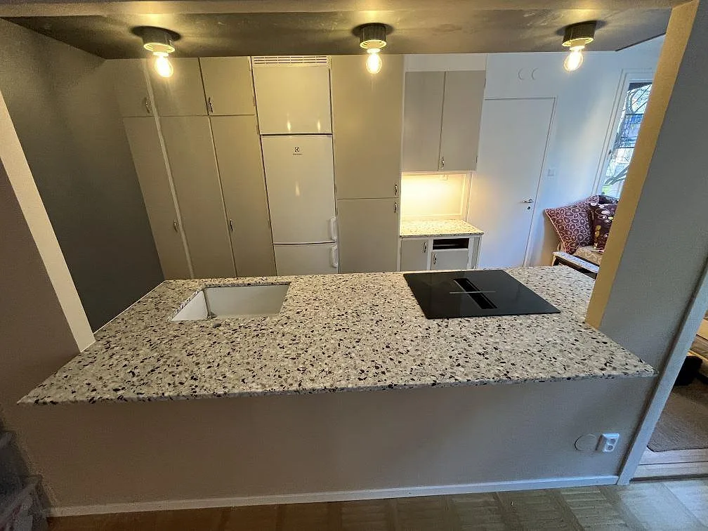 Köksbänkskiva i matt Terrazzo GV, terrazzo, med synlig häll i ett kök i Stockholm.