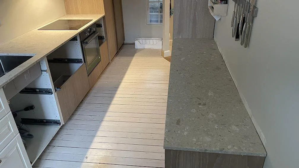 Köksbänkskiva i ljus Terrazzo Perlato Royal längs köksvägg med infälld häll och inbyggd ugn under montering i Göteborg.