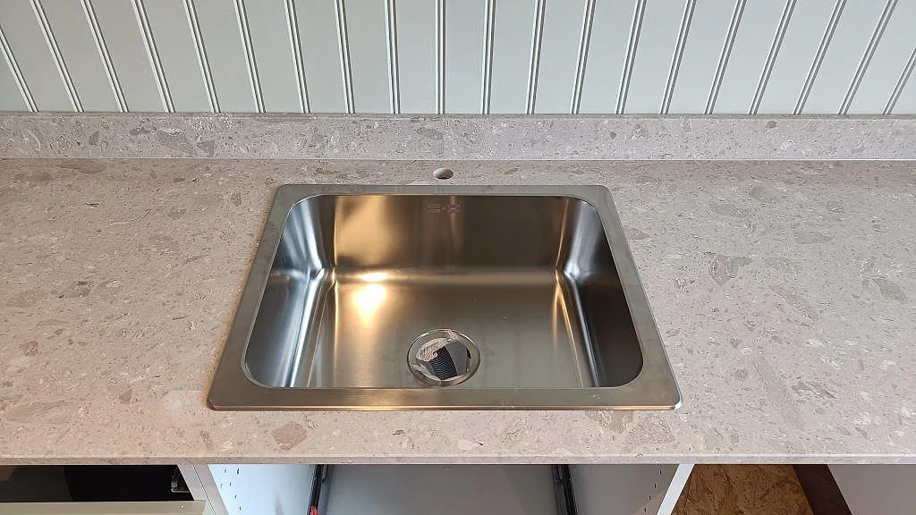 Närbild på matt köksbänkskiva i Terrazzo Perlato Royal med rostfri diskho och uppvikt stänkkant i Göteborg.