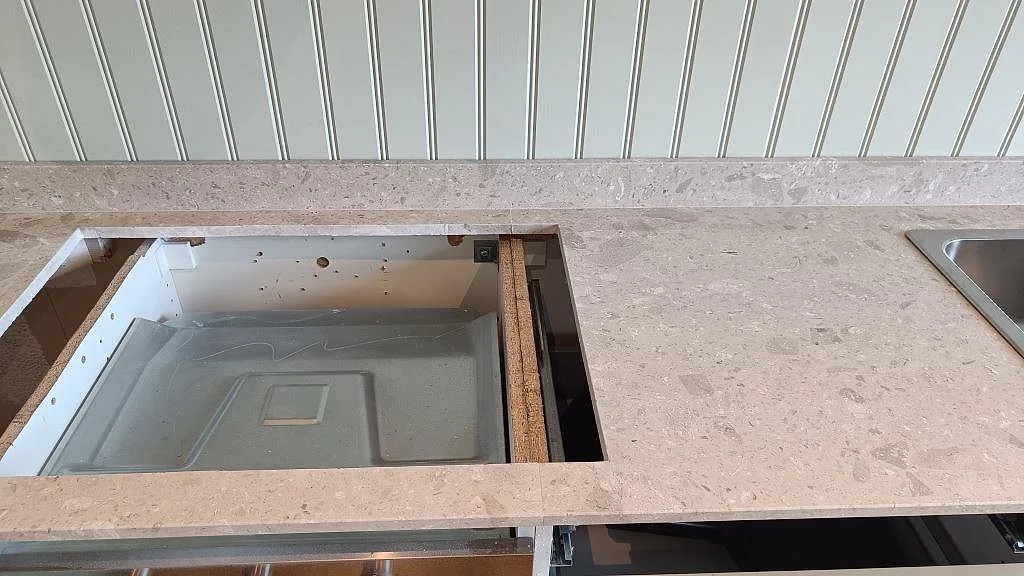 Detalj av matt Terrazzo Perlato Royal vid spisöppning och rostfri diskho i ett kök under montering i Göteborg.