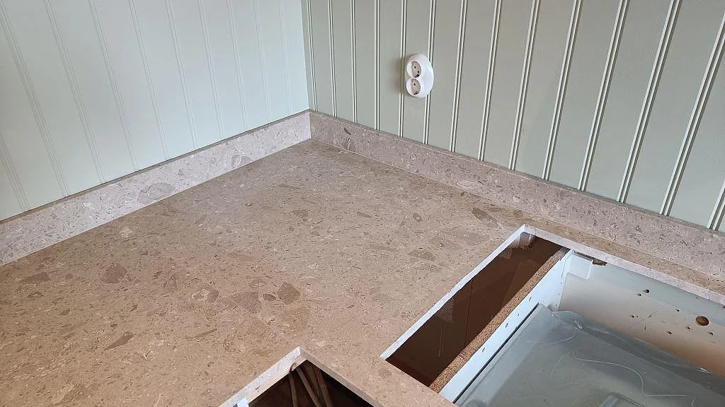 Hörnsektion i matt Terrazzo Perlato Royal med uppvikt stänkkant och öppning vid spisen i Göteborg.