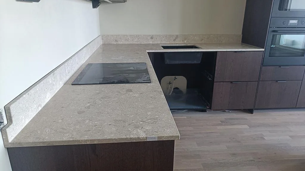 L-formad köksbänkskiva i Terrazzo Perlato Royal terrazzo, matt, med svart häll och underlimmad svart diskho i Helsingborg.