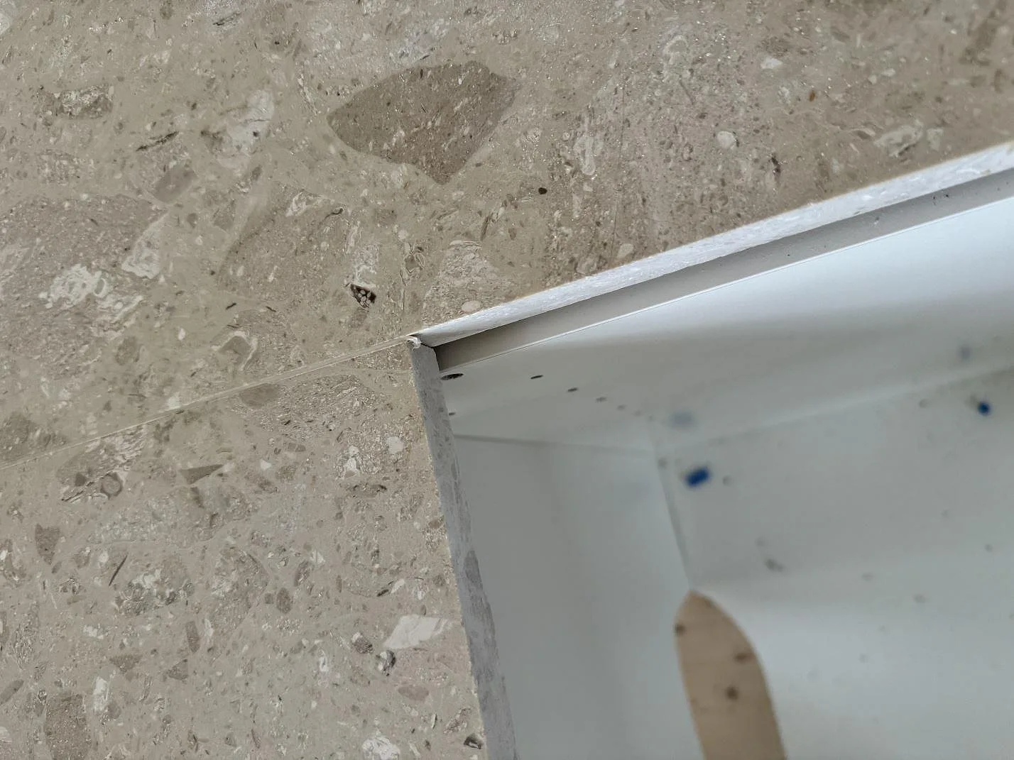 Detaljbild av bearbetad kant och urtag i matt Terrazzo Perlato Royal under köksmontering i Hindås.