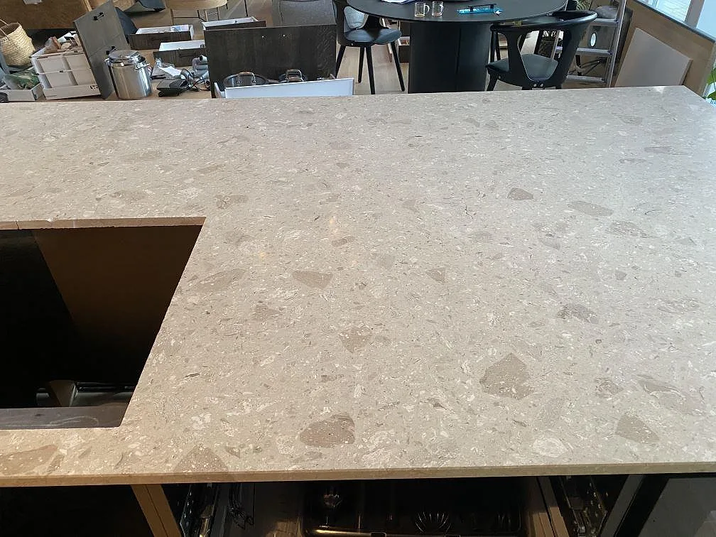 Köksö i Terrazzo Perlato Royal med matt terrazzoyta och varm krämvit ton i ett kök i Höllviken.