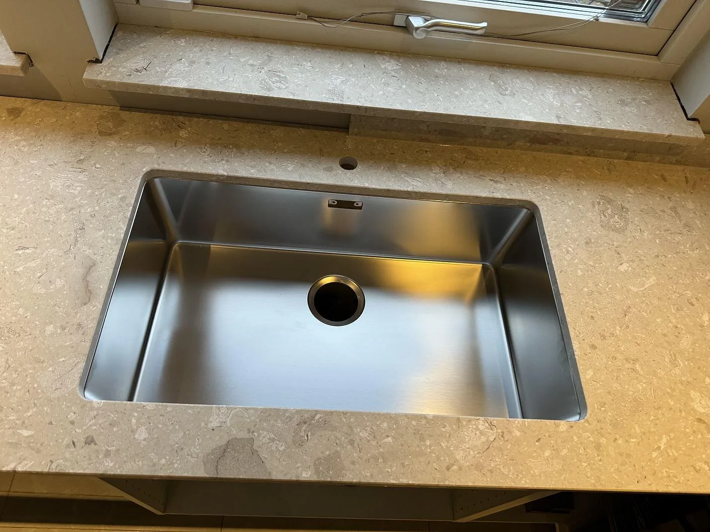 Närbild på underlimmad rostfri diskho i en matt terrazzo bänkskiva av Terrazzo Perlato Royal i Höllviken.