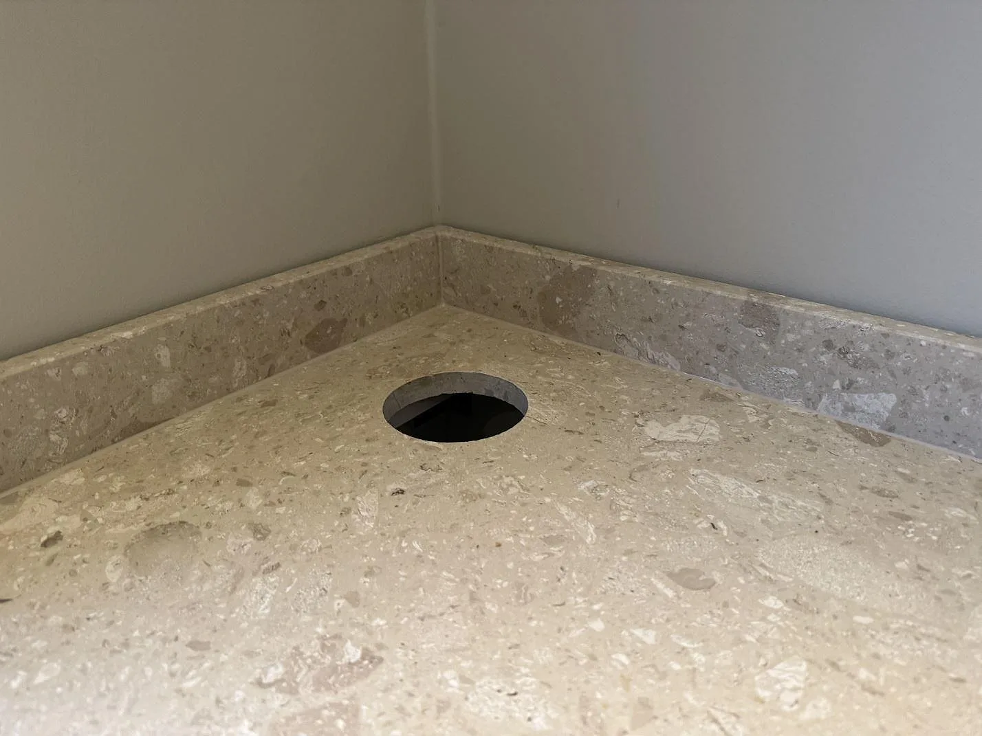 Detalj av matt Terrazzo Perlato Royal med rund håltagning, låg stänkkant och terrazzo struktur i Höllviken.