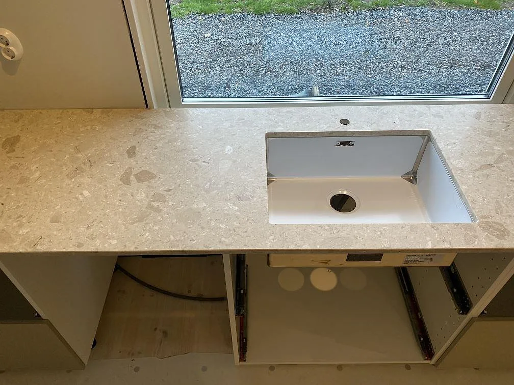 Matt köksbänkskiva i Terrazzo Perlato Royal med underlimmad diskho framför fönster i ett kök i Kungsbacka.