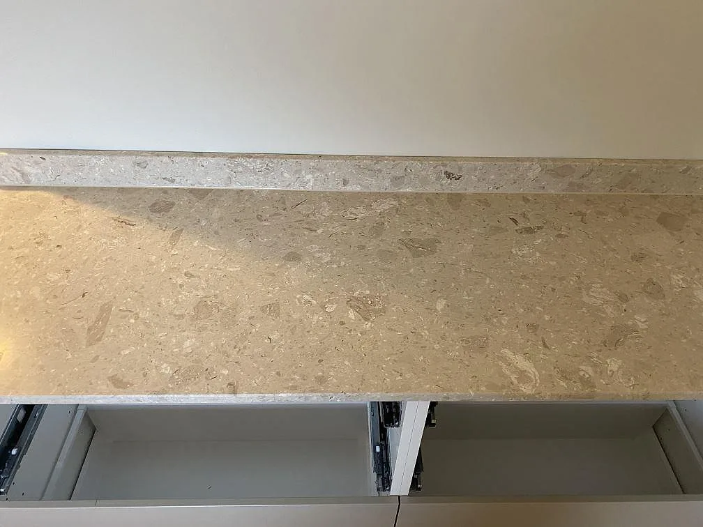 Detalj av bänkskiva i matt Terrazzo Perlato Royal med uppvikt stänkkant och ljusa stenfragment i Kungsbacka.