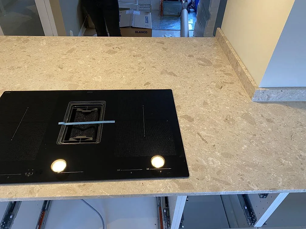 Infälld induktionshäll med nedfälld fläkt i köksö av Terrazzo Perlato Royal, matt beige terrazzo, i Kungsbacka.
