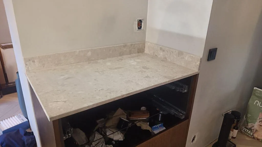 Kort bänkskiva i matt Terrazzo Perlato Royal med uppvikt stänkkant ovan mörka köksstommar i Limhamn.
