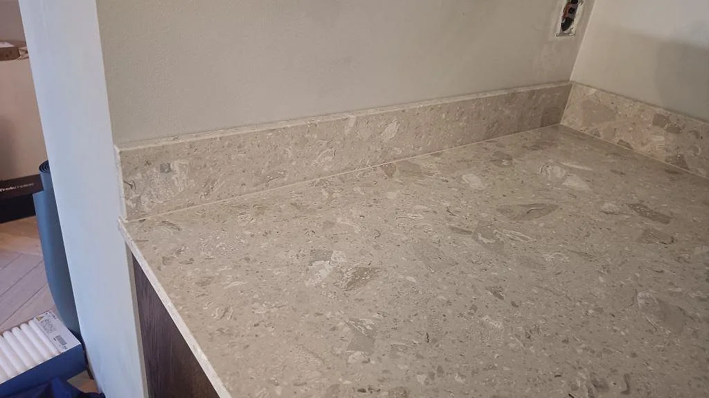 Närbild på matt Terrazzo Perlato Royal som köksbänkskiva med matchande stänkkant och beige terrazzo-mönster i Limhamn.