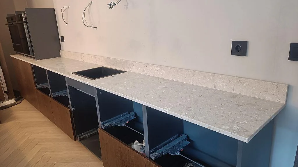 Köksbänkskiva i beige Terrazzo Perlato Royal, matt, med låg stänkkant och underlimmad rostfri diskho i ett kök i Limhamn.