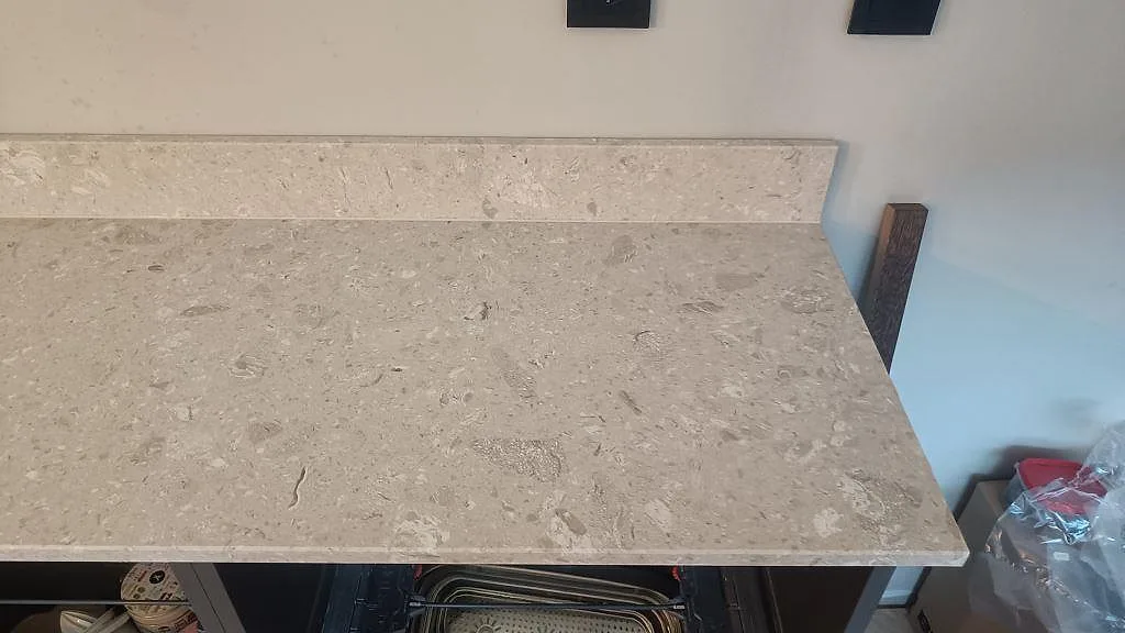 Detalj av den långa köksbänken i beige Terrazzo Perlato Royal med låg stänkkant och synlig terrazzo-struktur i Limhamn.