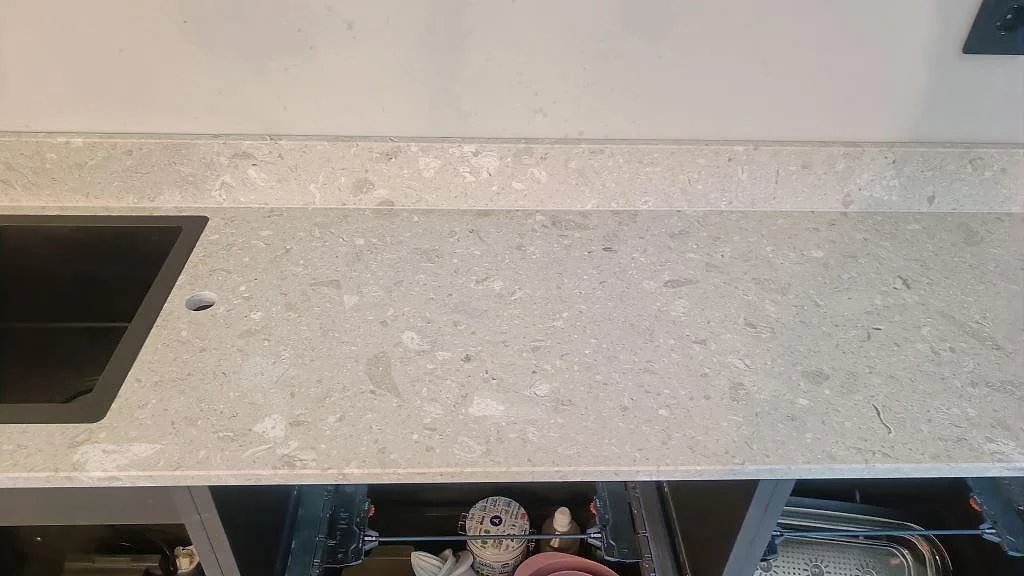 Närbild på matt Terrazzo Perlato Royal med underlimmad rostfri diskho, blandarhål och stänkkant i Limhamn.