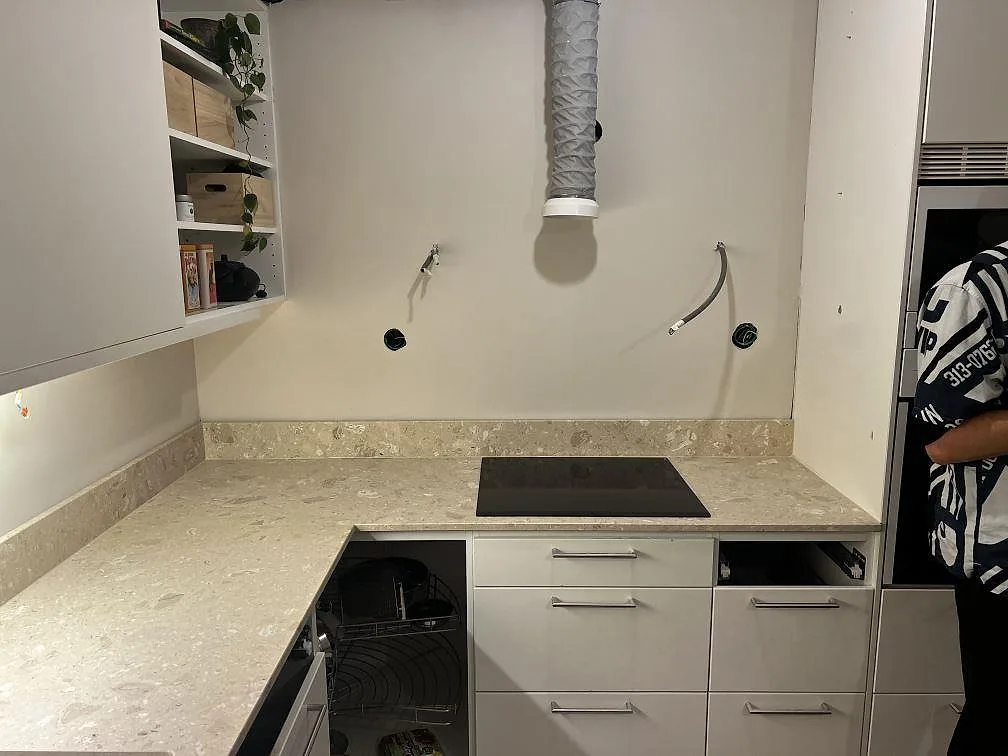 Köksbänkskiva i beige Terrazzo Perlato Royal, matt, med induktionshäll och uppvikt stänkkant i ett kök i Malmö.