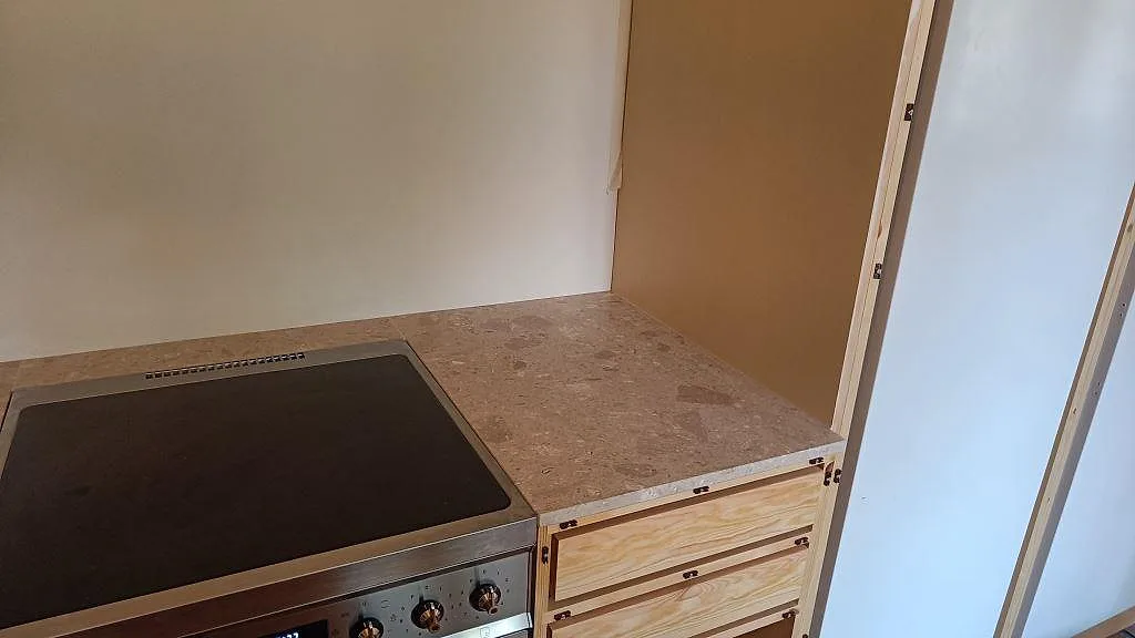 Sidovy av matt Terrazzo Perlato Royal köksbänk vid fristående spis och ljusa väggar under montering i Malmö.