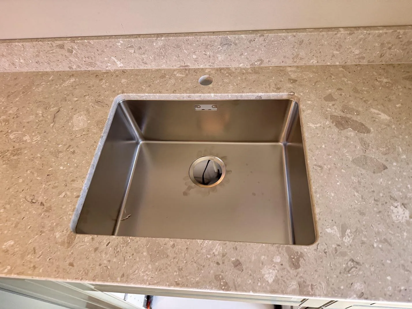 Detalj av rostfri diskho i köksbänkskiva av Terrazzo Perlato Royal, matt, med terrazzo runt ho och stänkkant i Malmö.