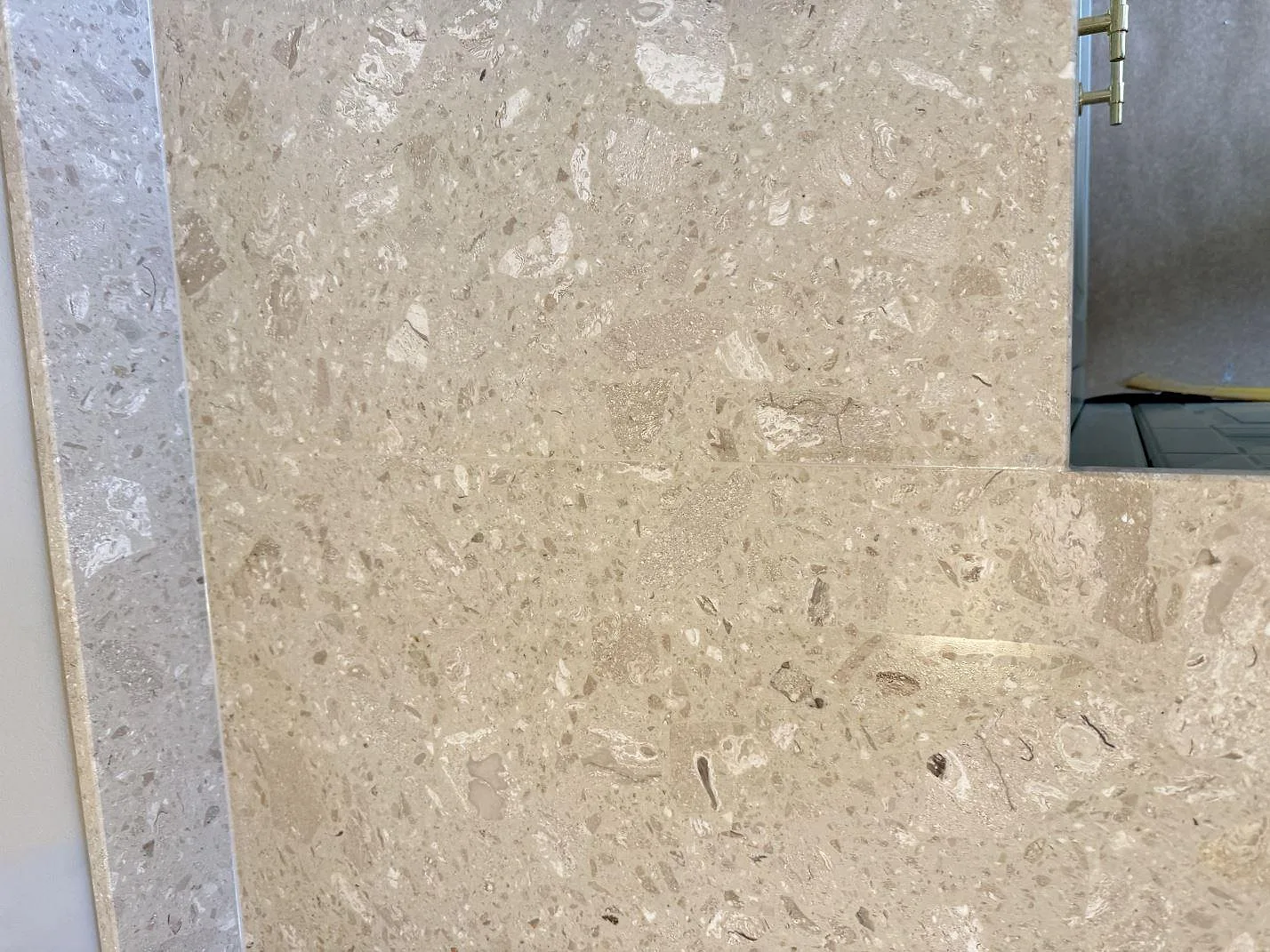 Ytdetalj av Terrazzo Perlato Royal, matt terrazzo, med stenfragment och kant mot spisöppning i Malmö.