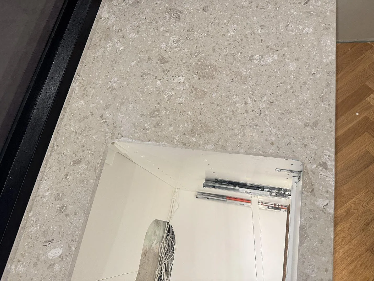 Detalj av matt Terrazzo Perlato Royal runt en rektangulär urtagning i köksbänkskivan i Odense SV.