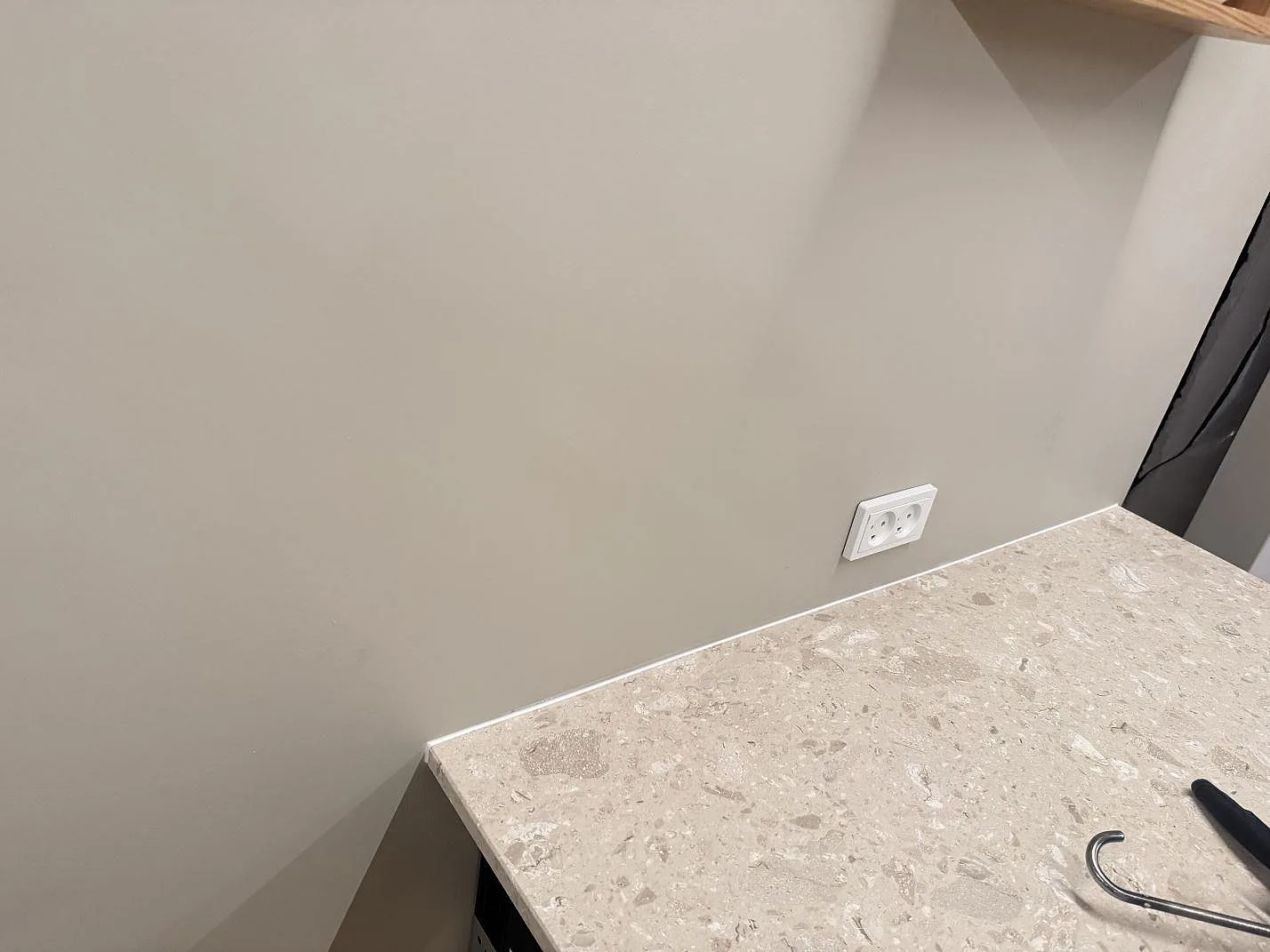 Detalj av matt Terrazzo Perlato Royal längs vägg med eluttag under köksmontering i Odense SV.