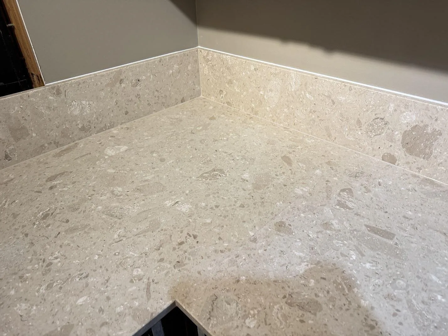 Närbild på hörn och uppvikt stänkkant i matt Terrazzo Perlato Royal över köksstommar i Sjöbo.