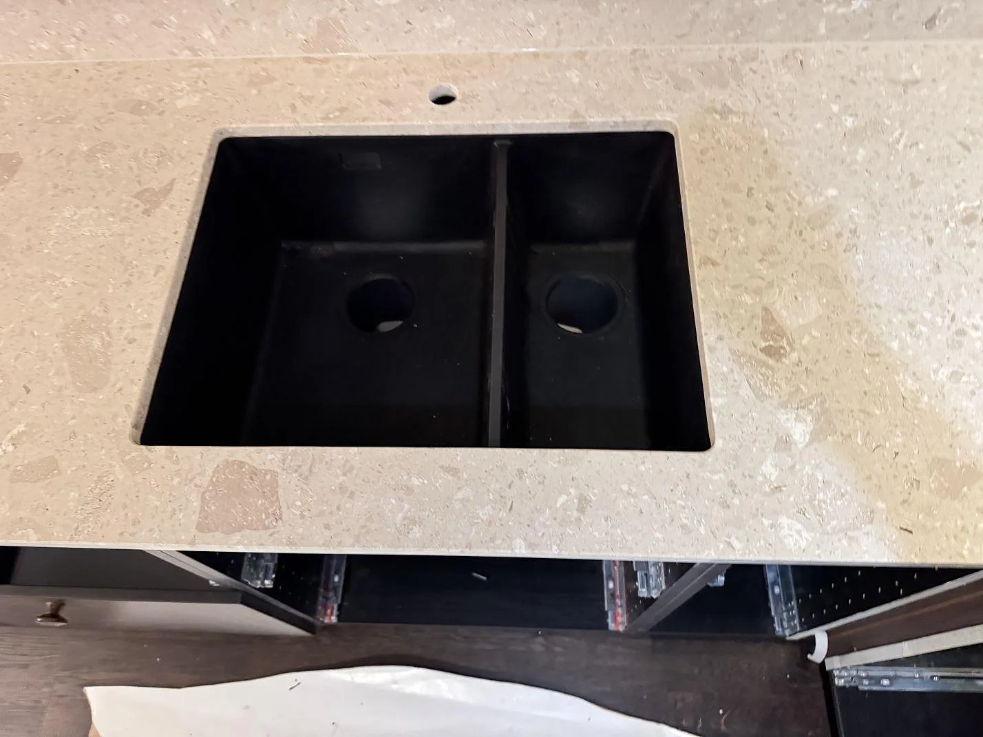 Närbild på svart diskho i en matt bänkskiva av Terrazzo Perlato Royal med beige stenfragment i Sjöbo.