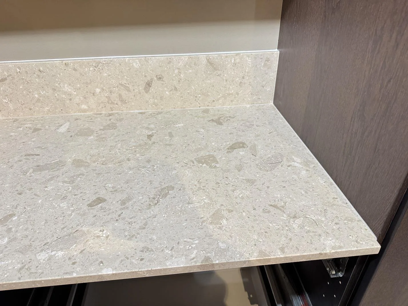 Detalj av matt Terrazzo Perlato Royal som köksbänkskiva och stänkkant intill mörk träinredning i Sjöbo.