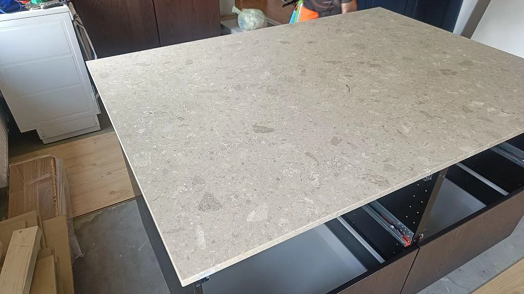 Köksö i matt Terrazzo Perlato Royal monterad på mörka köksstommar under pågående köksrenovering i Skurup.